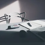 Bureau de travail avec ordinateur, calculatrice et bloc-notes, photographie illustrative.
