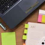 Préparation d’un dossier sur un bureau avec ordinateur et carnet, photographie illustrative.